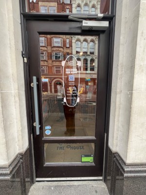 Black framed glass door. Push open via handle on left.