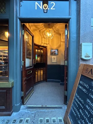 Facing wooden-framed glass doors ahead. Push golden metal handles in centre to open.