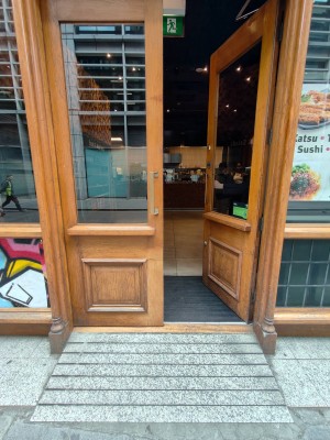 Facing entrance door. Wooden framed door. Push handles in centre to open.