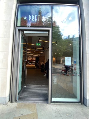 Glass door, with grey doorframe. Vertical silver handle along right. Push to open.