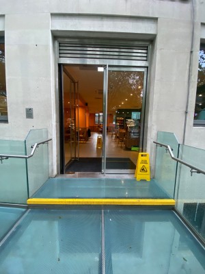 Double glass door, with metal grey doorframe. Handles at centre of door. Push to open.