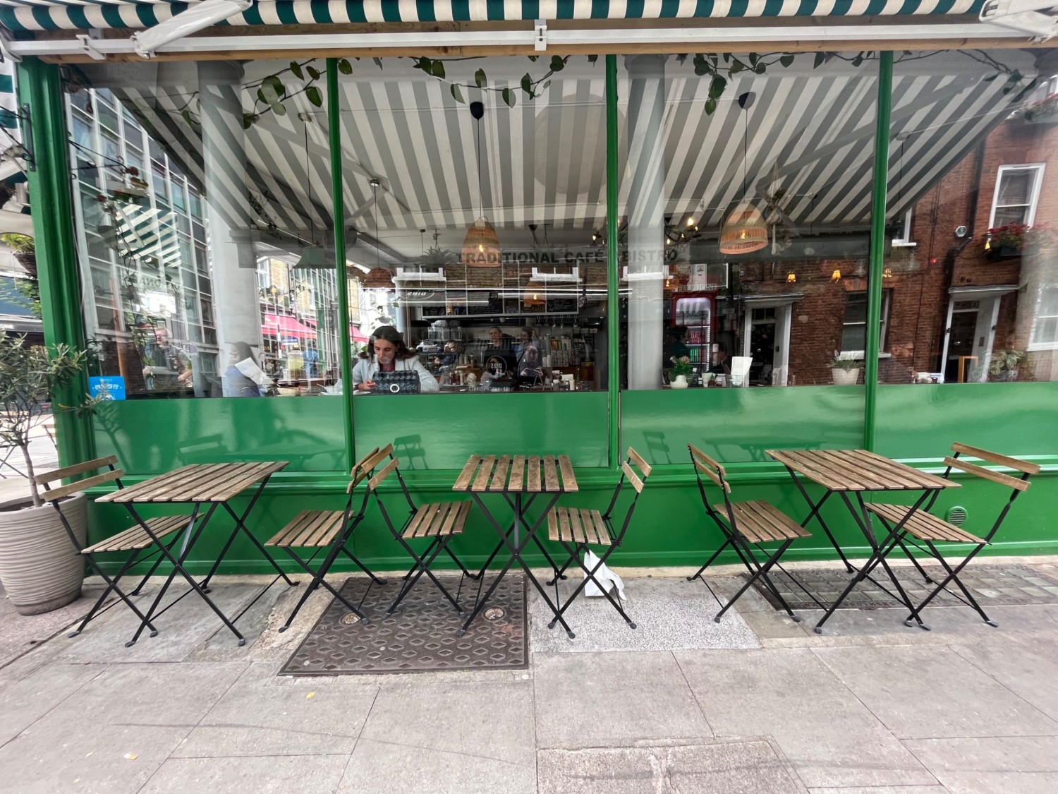 From pavement to left of entrance facing venue. Tables and chairs along venue wall ahead.