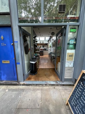 Double glass door with grey frame. Push golden handle on left of right door to open. Portable sign in front on right of door.