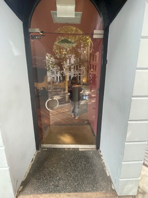 Glass door with handle at left, push to open.