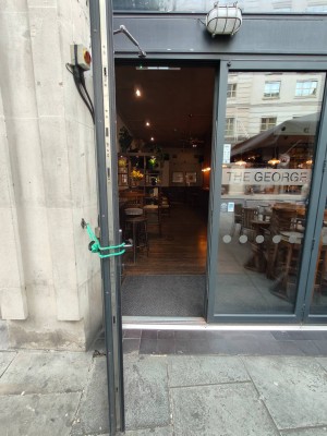 Facing entrance door. Push handle on right of left door to open.
