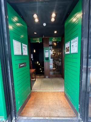 Double green wooden doors in black wooden frame. Push from centre to open.
