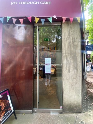 Glass door. Vertical silver handle along left. Push to open.