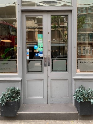 Double grey wooden doors with glass panels. Push from center to open.