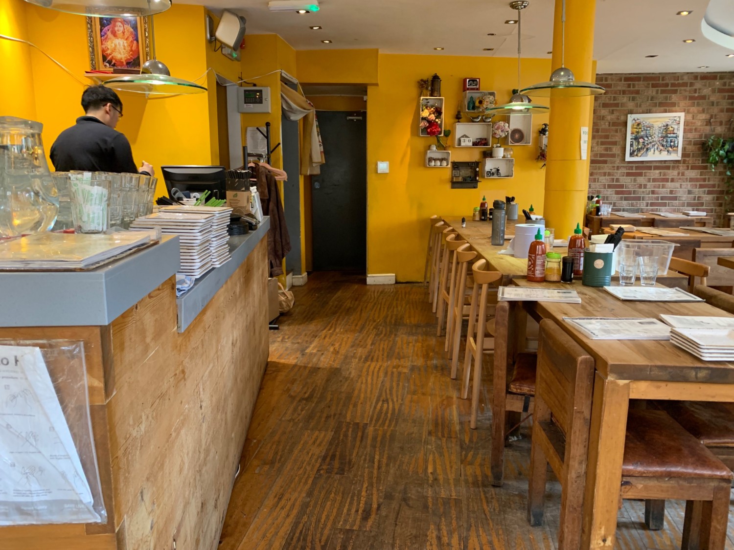 From beginning of counter, looking left. Counter along left wall. Path down center. Seating along right side.
