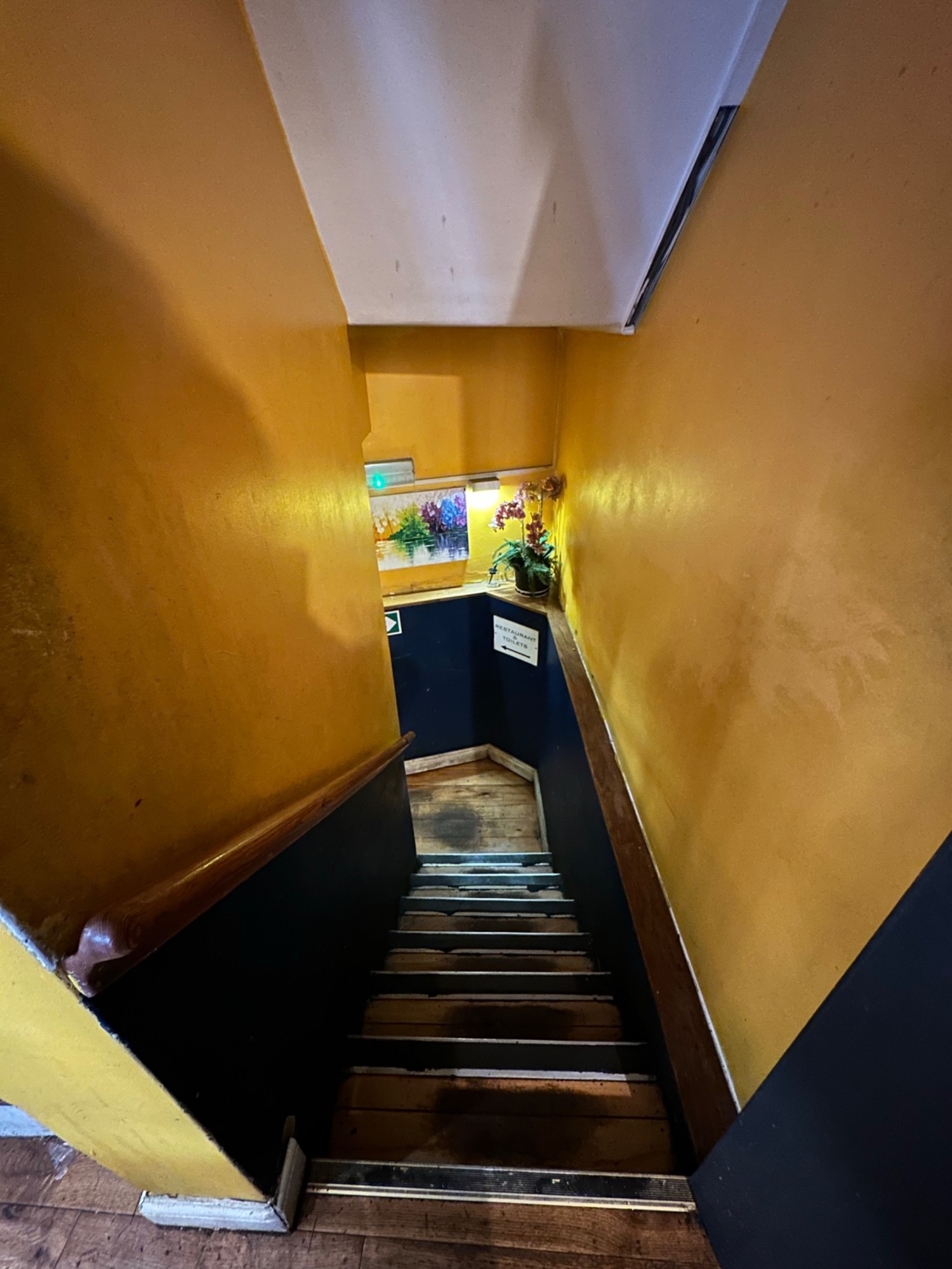 From archway looking left at first flight of stairs ahead. Wooden handrail along left.