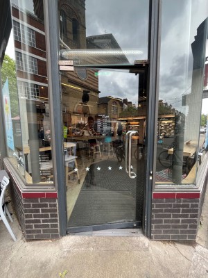 Grey framed glass door. Push open via handle on right.
