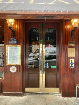 Double glass doors with dark wooden frame. Gold pads in middle, push to open.