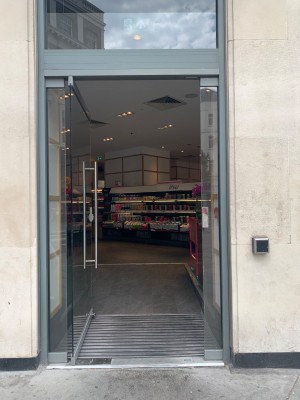 Single glass door with silver metal handle on right of door. Push to open.