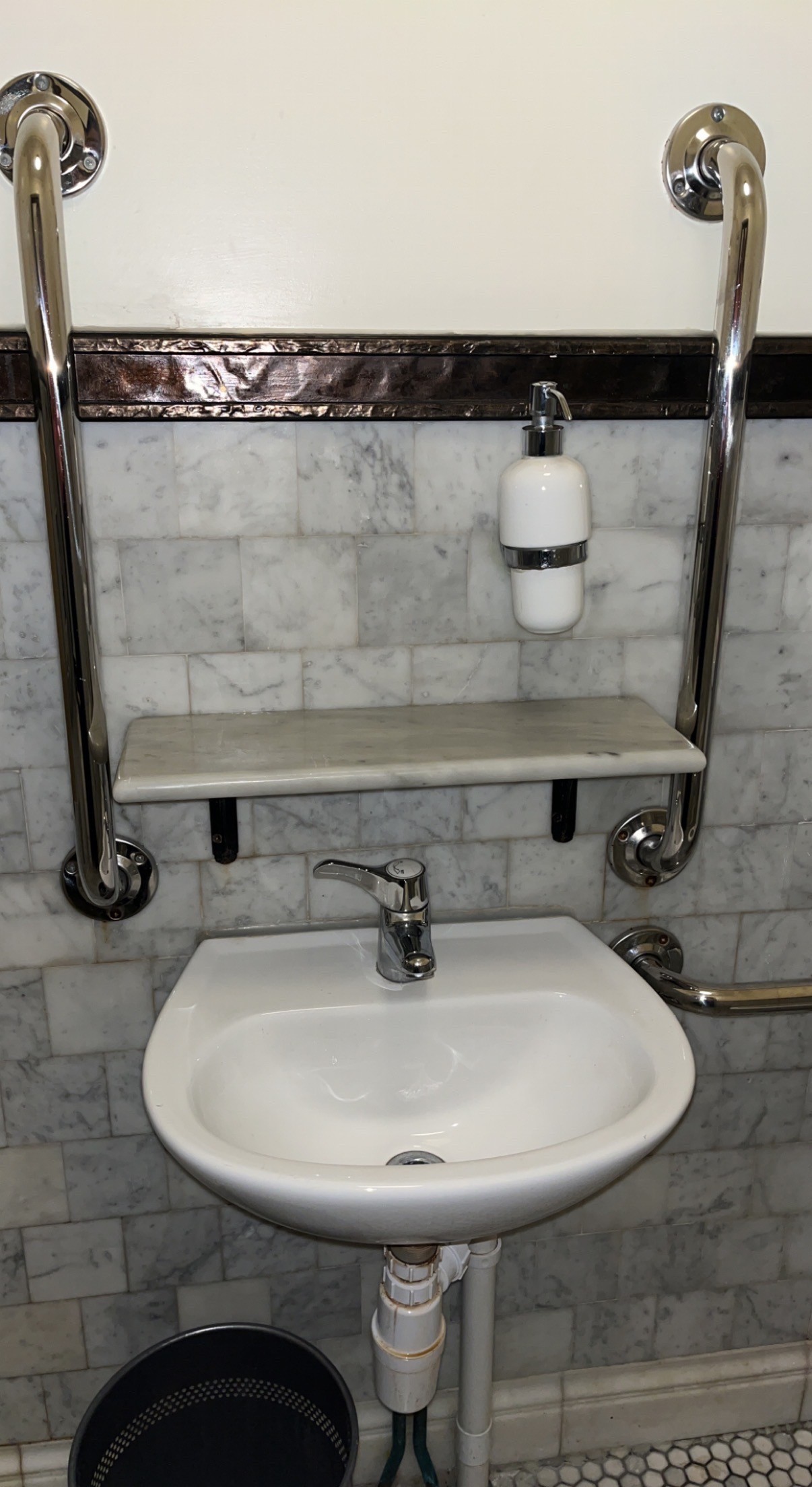 Shelf above sink and grab bar either side.
Soap in a dispenser above sink