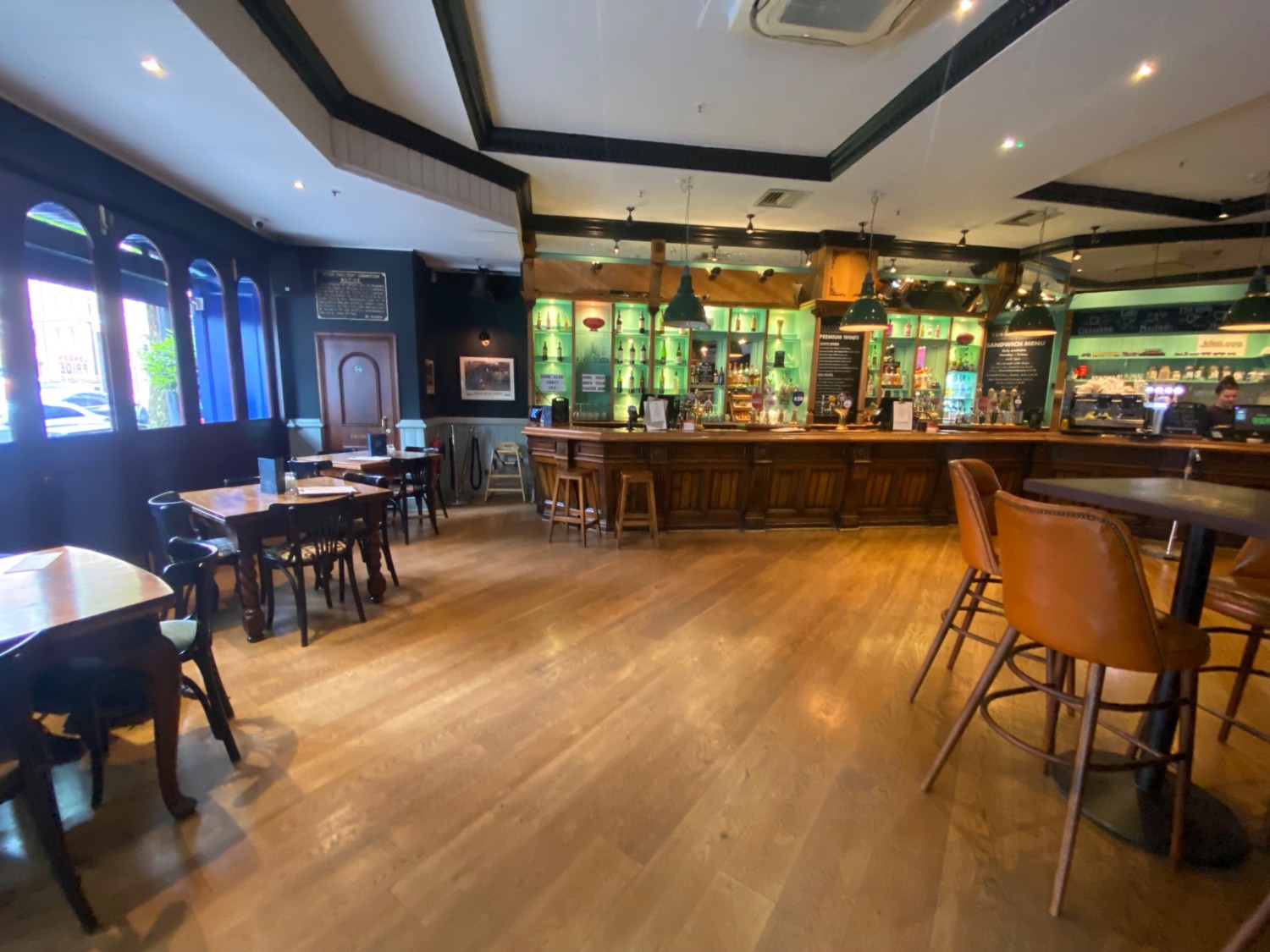 From entrance, facing left. Tables and chairs along left. Counter along back wall. High table and stools on right.