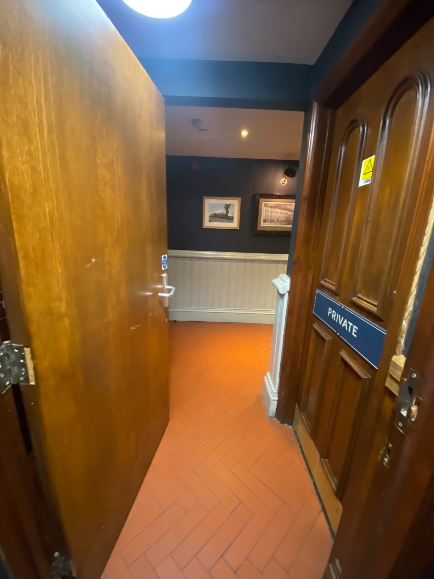 From sink, facing back at door. Silver handle on right. Push to open.