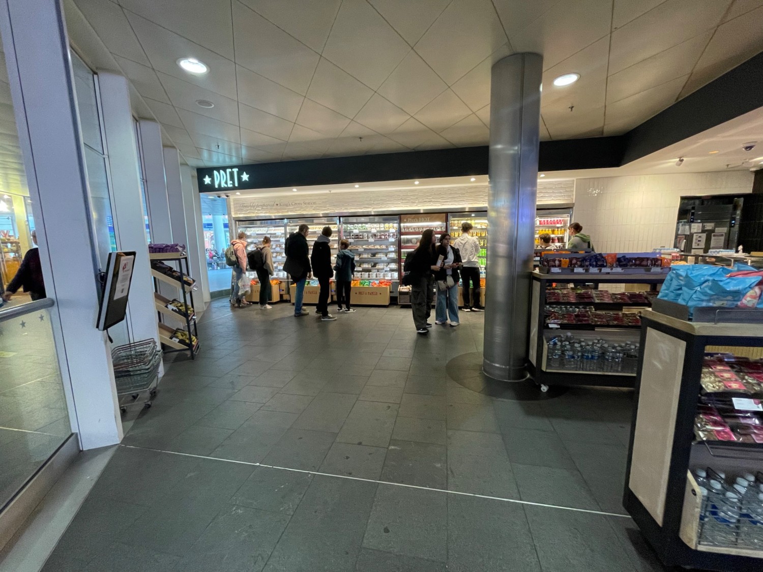 From entrance looking left. Wide space ahead.Two open shelves on right and one back left. Pillar in back right.  Fridges along back wall.