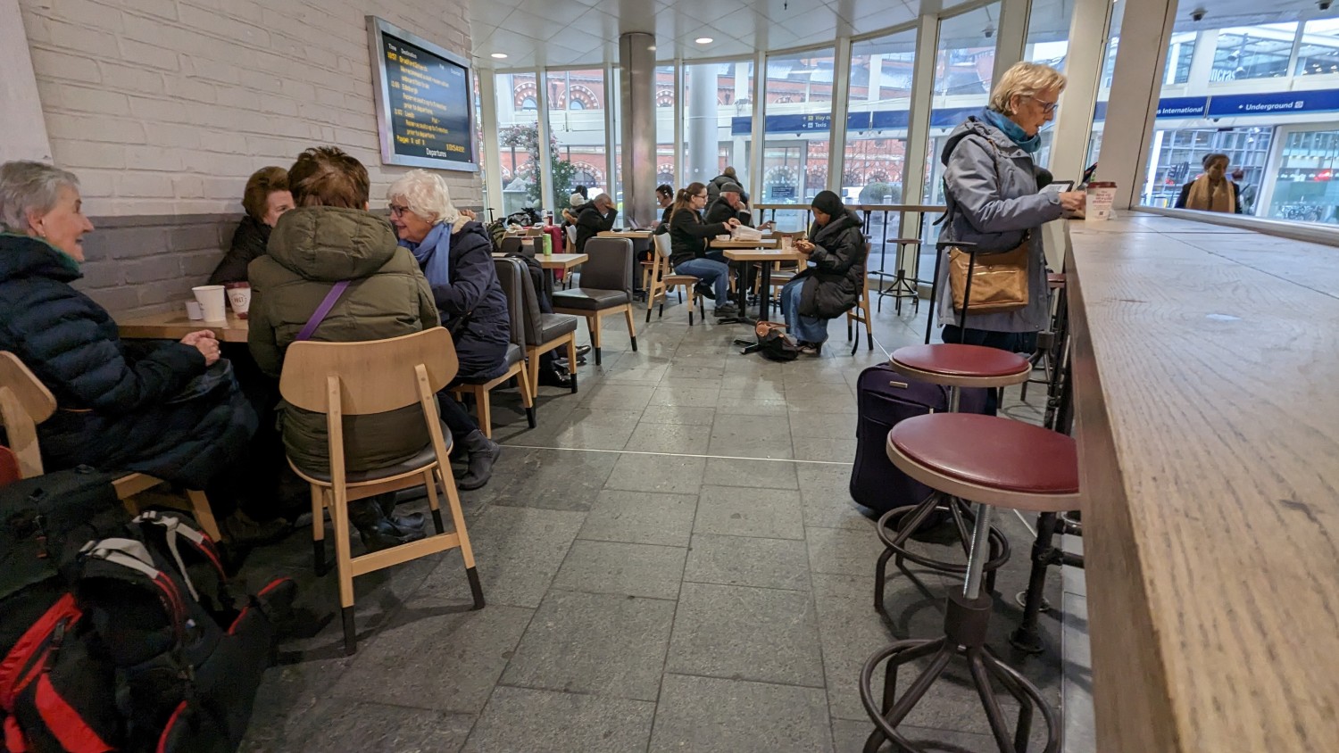 From mid path facing straight. Stools along right. Path in centre to more seating along back and back left. Table and chairs along left.