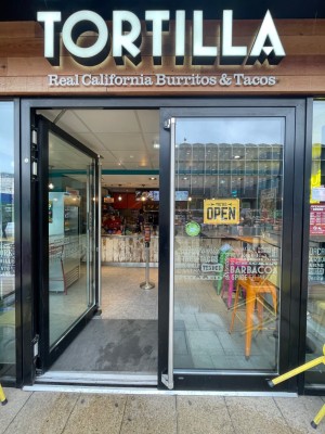 Double glass door with black frame. Push vertical metal handle from middle to open.