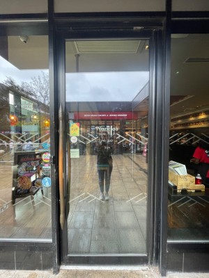 From path, facing left. Single glass door with black frame. Pull wooden vertical handle on left to open.