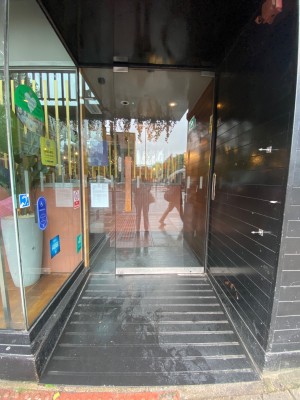 Glass door, with wooden vertical handle on left. Pull to open.
