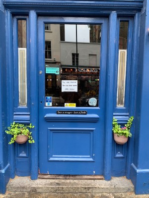 Blue wooden door with glass paneling ahead. Push from left to open.