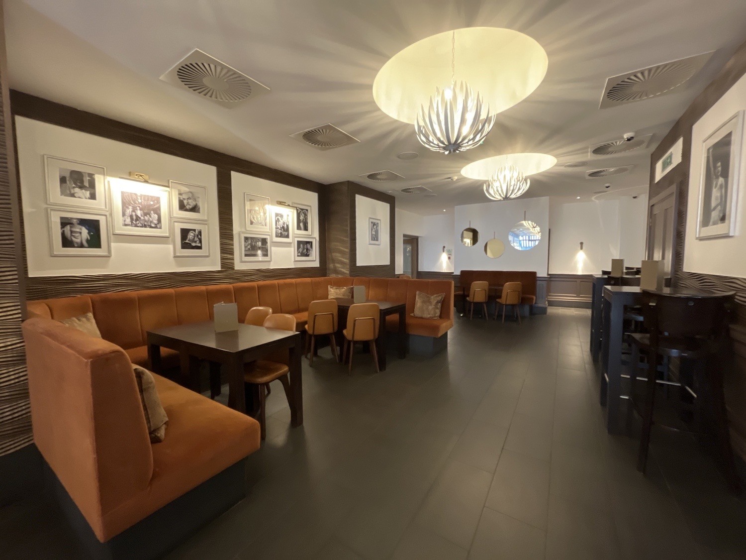 seating near back area, booths and sofas with seated height tables, high tables and stools near right wall