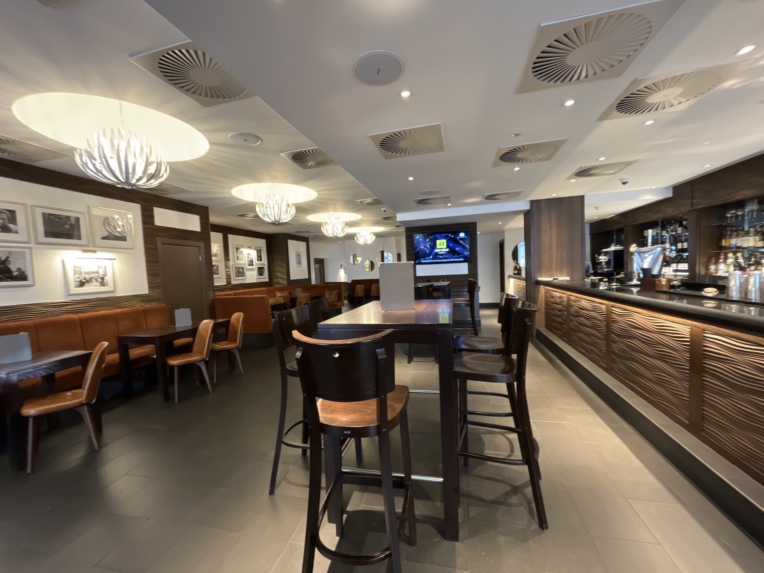 seating near front bar area, seated high tables and benches along left wall and high tables and stools in center