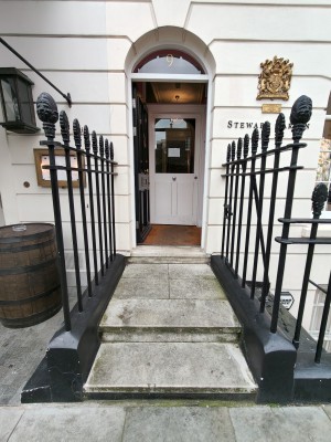 Two steps up to landing before first preceding door. Black metal railing on both sides.