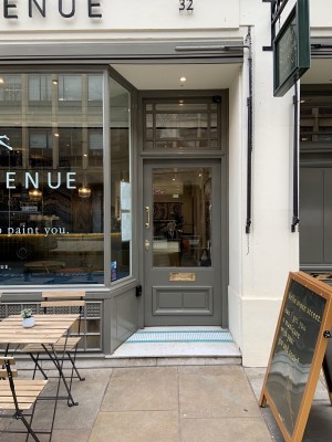 The entrance door is to the right hand side of the venue. It is up a step and dips in from the front window. It pushes to open from the left hand side by a handle which is relatively high up on the door.