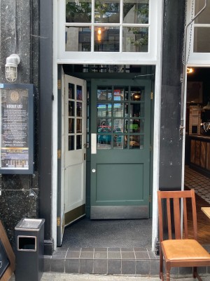 Access via white wooden door with glass panels. Push open via metal pad on right.