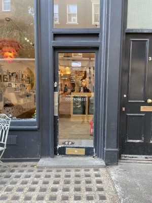 Black wood-framed glass door ahead. One step before doorway. Push on left side of door to open.