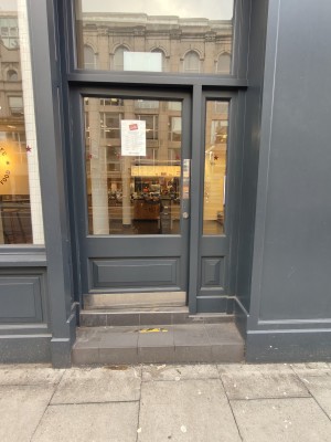 Facing grey framed glass door. Push from right to open.