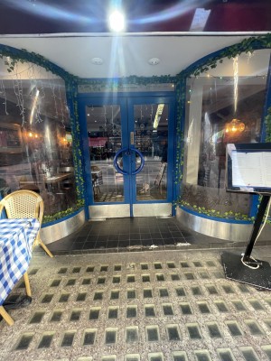 View of entrance from the street. There is a small step at the entrance, followed by a set of double doors. The doors pull open inwards.