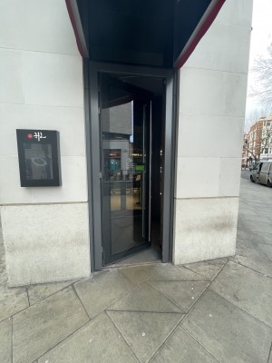 View of main entrance to the venue. There is a single glass door which pushes into the restaurant from the right. There is a small bump.
