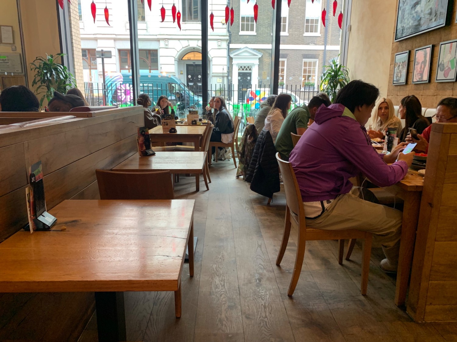 From end of path, looking left. Tables and chairs along left wall divider. Path down center. Half booths along right wall.