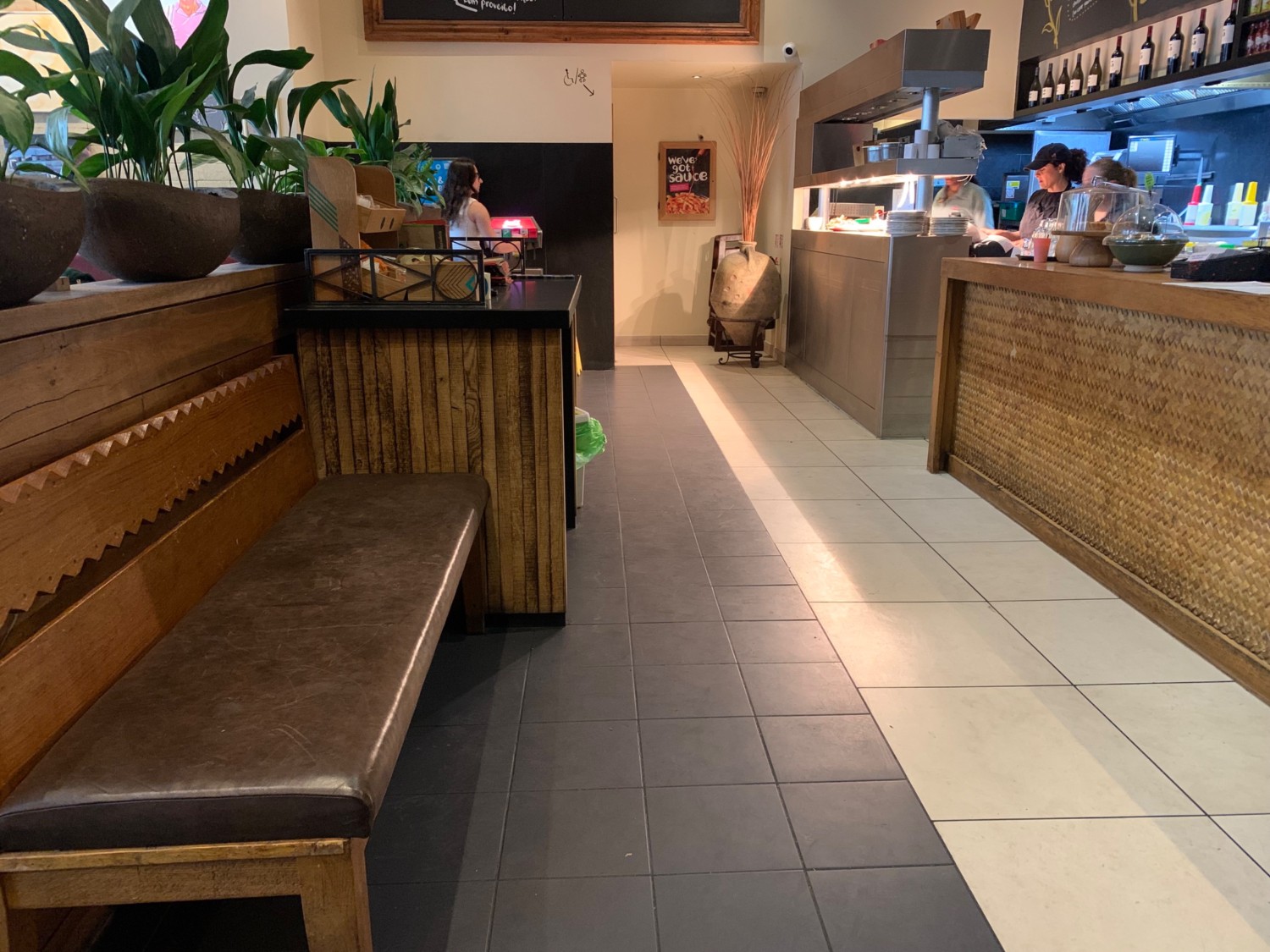 From back right of main area, looking left. Bench on left, followed by stand. Path down center. Counter along right wall.