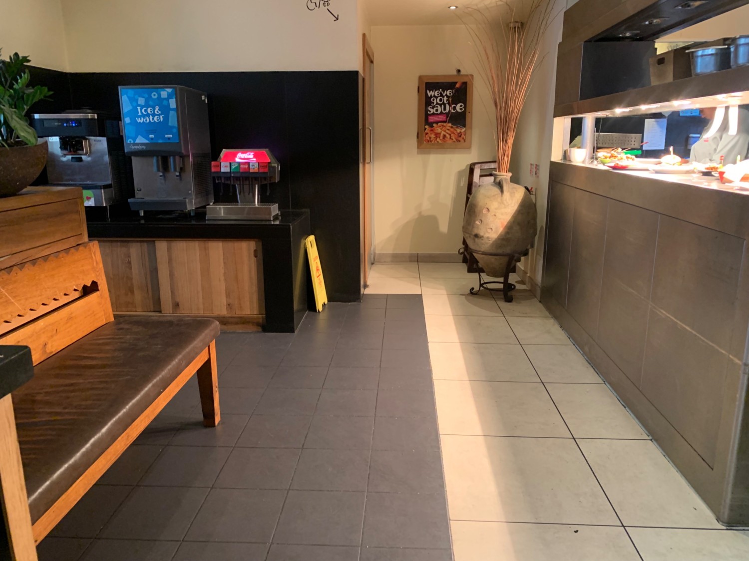 From stand, looking straight. Second bench on left, after stand. Path straight to toilet area ahead. Counter along right wall.