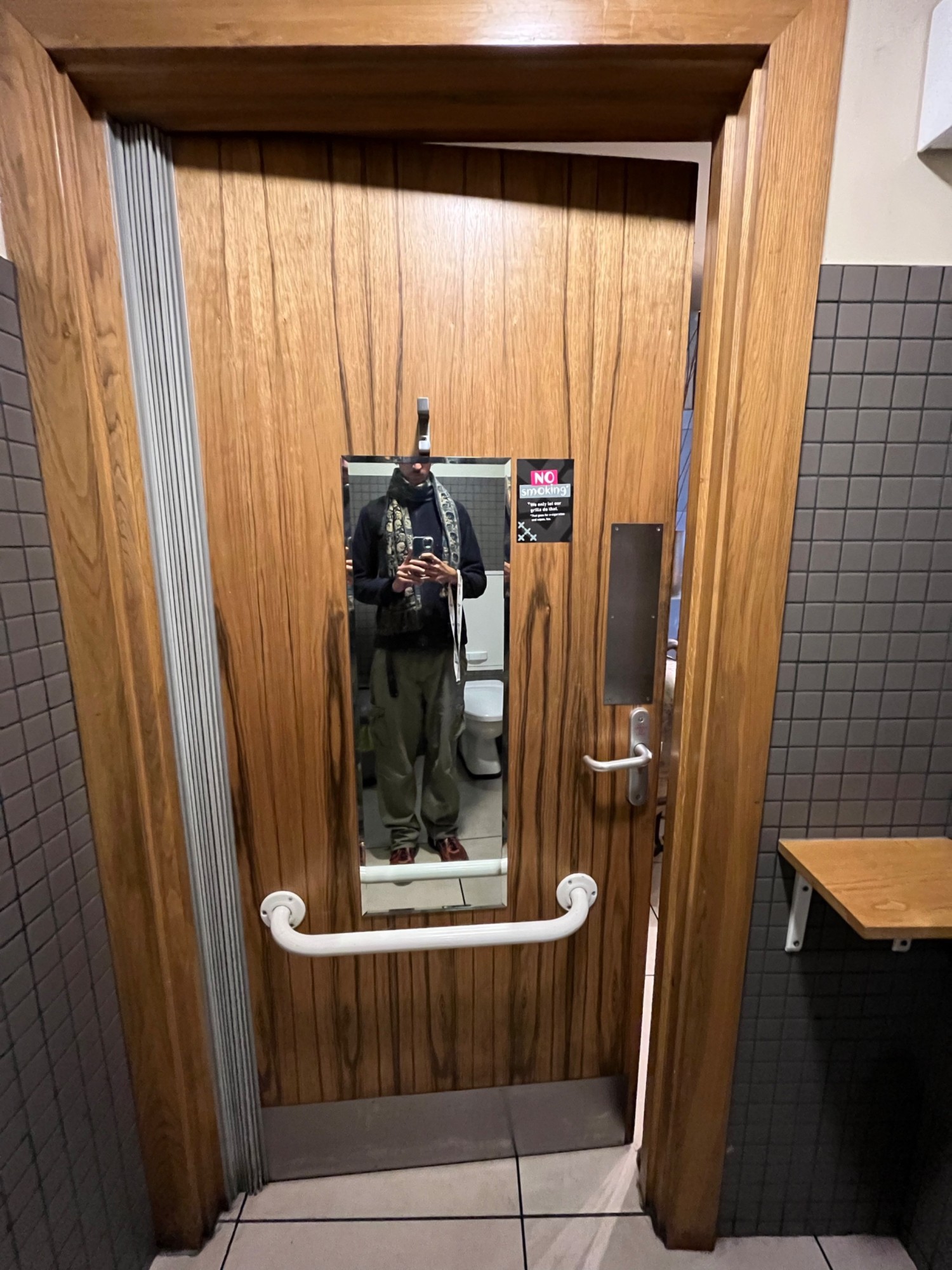 From toilet looking back. Brown door. Push open via handle on right. Hook on door.