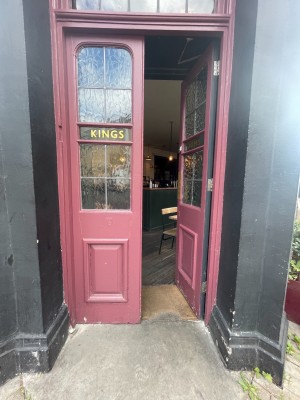 Red doors with glass panel ahead. Push in centre to open.