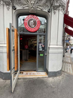 Grey glass door with long wooden handle at right, pull to open. Bell for assistance at right.
