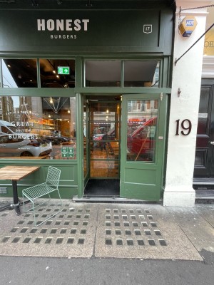 Green wood-panelled glass door ahead. One step up before door. Pull brass handle on left to open.
