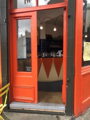 Glass paneled doors with orange frame. Push in center to open. Step up at foot of door. Doormat following.
