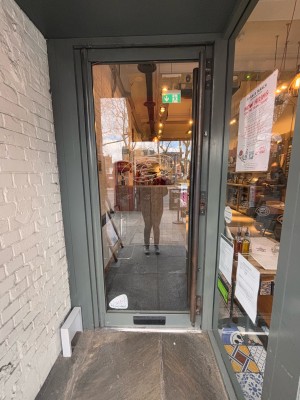 Glass door with grey doorframe ahead. Pull metal handle at center right to open.
