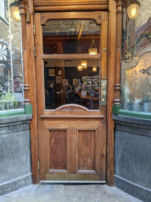 Glass and wood door with metal handle on right. Pull to open.
