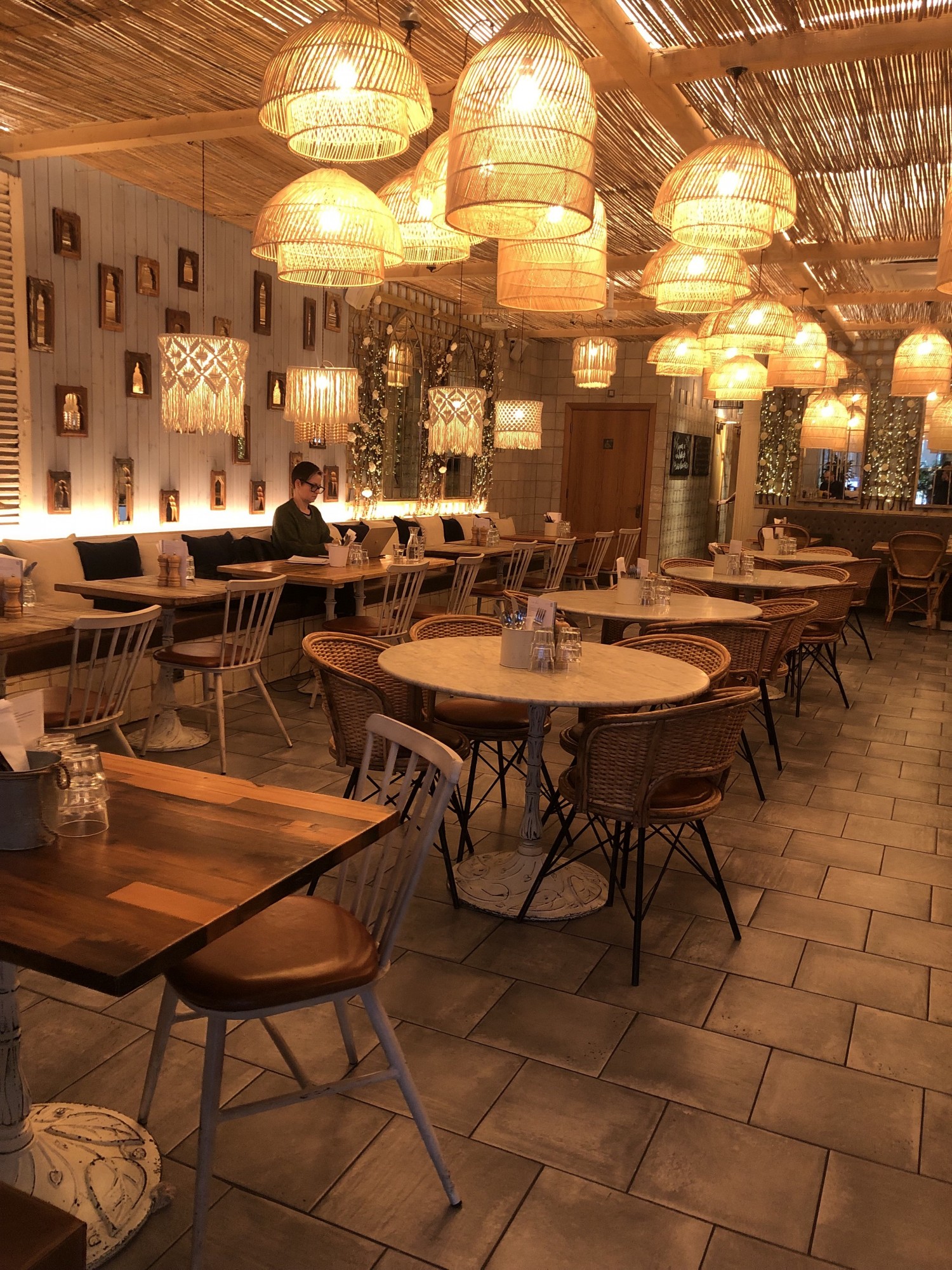 View from the entrance. On the left hand side there are seating height tables for 4 people, then a pathway and then seating height tables with a bench next to the wall.