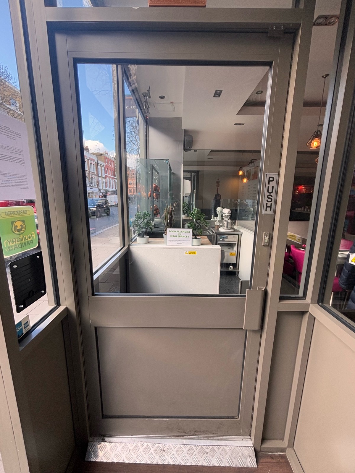 From door facing left. Second glass door with grey frame ahead. Push at center right to open.