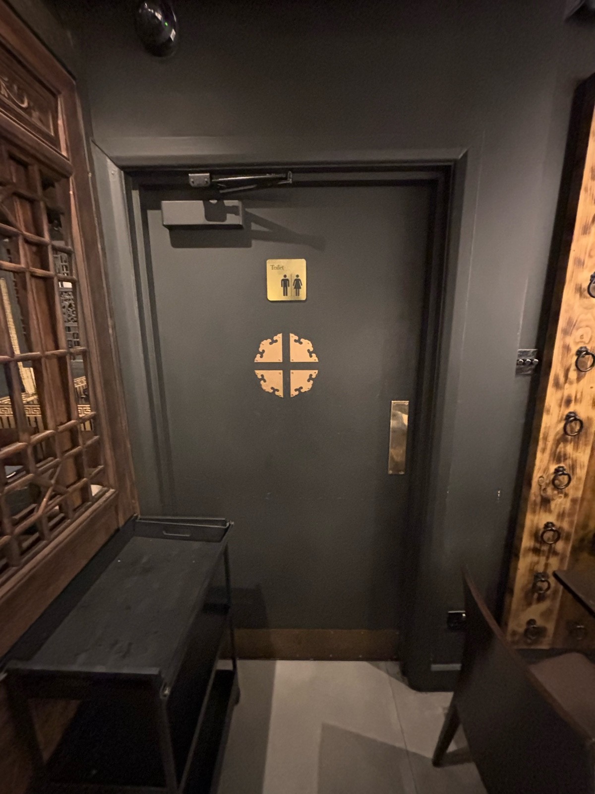 From back of back area facing straight. Grey bathroom door ahead. Push metal plate at center right to open.