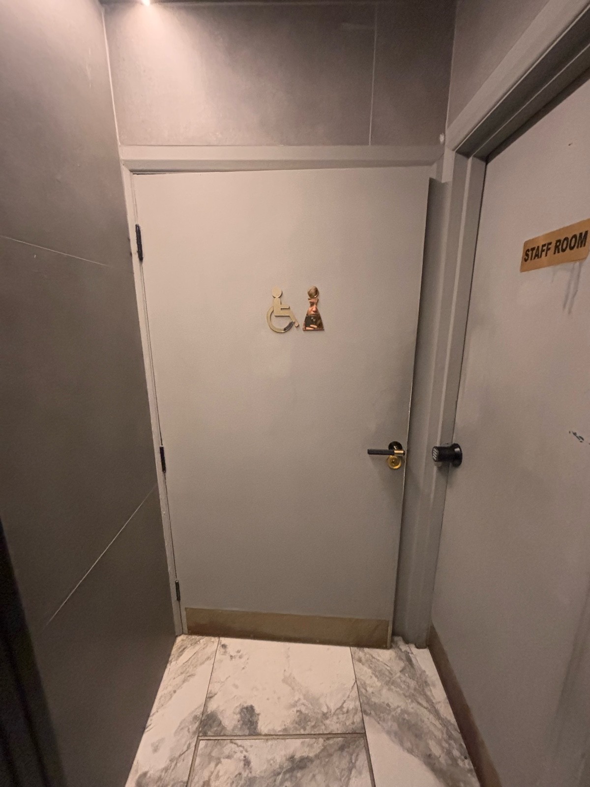 From door facing straight. White bathroom door ahead. Pull golden metal handle at center right to open.