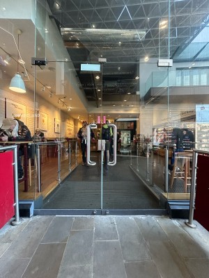 Glass doors ahead with silver metal handles in centre. Pull to open. Red and silver dividers on both sides of doors.
